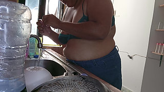 Mother-in-law cleans in the kitchen in bra