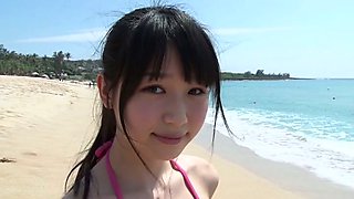 Slim Asian girl Tsukasa Arai walks on a sandy beach under the sun